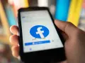 Dłoń trzyma smartfon z logo Facebooka. Chcesz wiedzieć, jak usunąć FB?