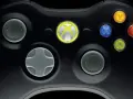 Zbliżenie na czarny kontroler Xbox 360 z podświetlonym logo Xbox i kolorowymi przyciskami.