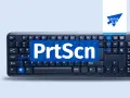 Klawiatura z widocznym napisem "PrtScn" na niebieskim tle. To wycinek ekranu skrót do robienia zrzutów.
