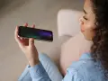 Kobieta trzyma telefon, na ekranie którego widać ikonę mikrofonu, sugerującą aplikację do nagrywania rozmów.