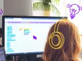Dziewczynka w słuchawkach tworzy kod w Scratch po polsku, ucząc się programowania.