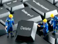 Figurki robotników w niebieskich kombinezonach próbują usunąć klawisz "Delete" z klawiatury. Działają jak incogni, usuwając niechciane dane.