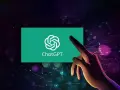 Dłoń dotyka ekranu z logo ChatGPT, symbolizując interakcję z zaawansowaną sztuczną inteligencją GPT.