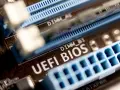 Zbliżenie na płytę główną z widocznym napisem "UEFI BIOS" i złączami RAM. W tle widać oznaczenie DIMM_A1, a poniżej DIMM_B1. Ten układ jest kluczowy dla bezpieczeństwa systemu, podobnie jak moduł **TPM 2.0**.