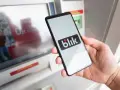 Dłoń trzyma smartfon z logo Blik. Czy Blik jest tylko w Polsce? Płatność zbliżeniowa przy bankomacie.