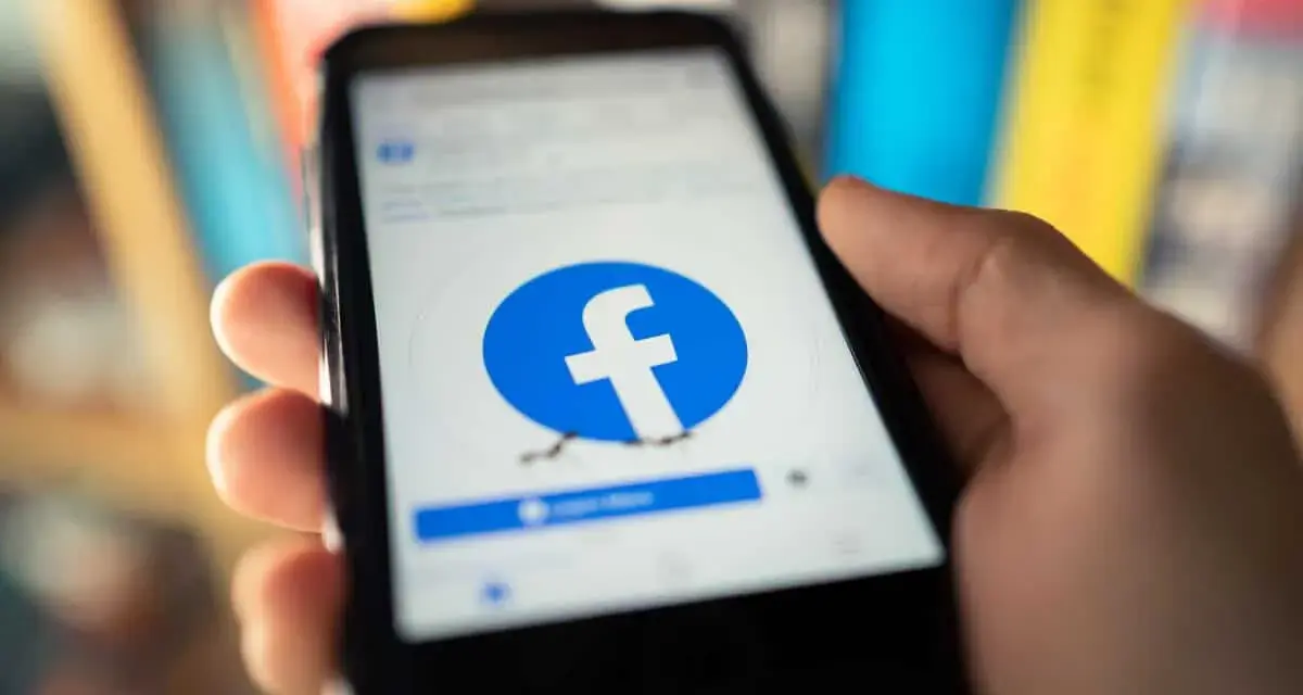Dłoń trzyma smartfon z logo Facebooka. Chcesz wiedzieć, jak usunąć FB?