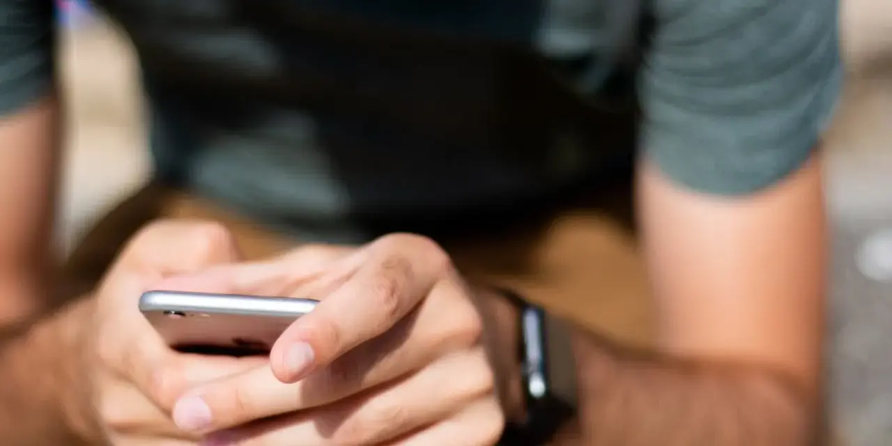 Mężczyzna z zegarkiem na ręku korzysta z telefonu, ucząc się, jak sparować zegarek z telefonem.