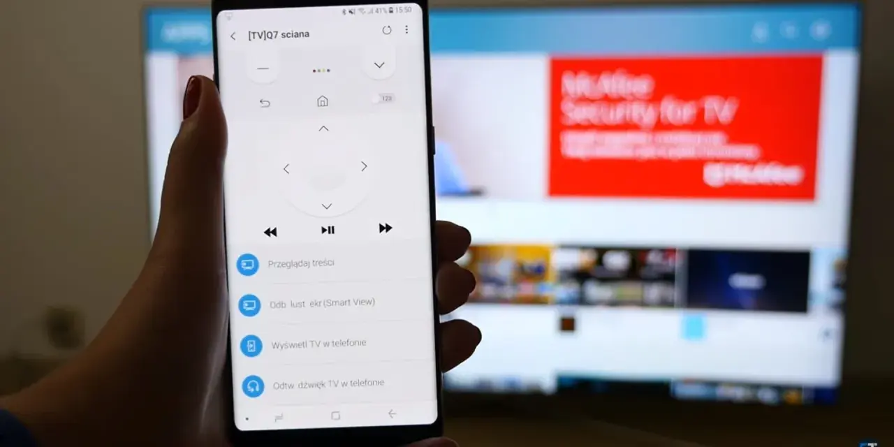 Smartfon z aplikacją do sterowania TV, umożliwiający screen mirroring. Na ekranie telefonu widoczny pilot, a na telewizorze reklama McAfee.