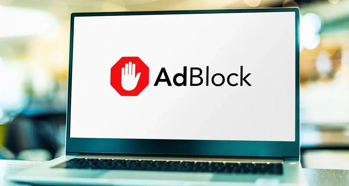 Laptop z logo AdBlock. Dowiedz się, jak wyłączyć adblocka, aby zobaczyć treści.