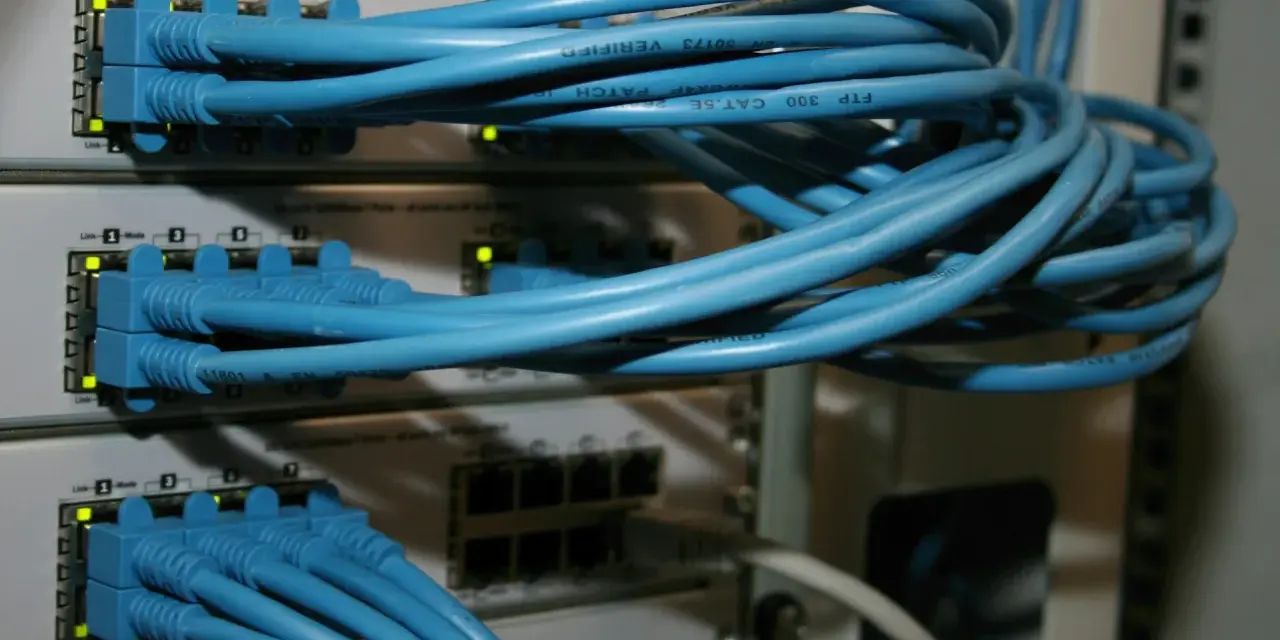 Sieć komputerowa z niebieskimi kablami Ethernet podłączonymi do przełączników. Połączenia peer to peer tworzą infrastrukturę.