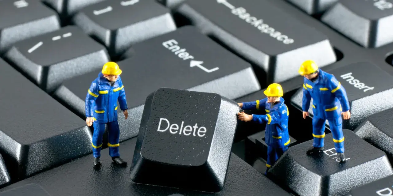 Figurki robotników w niebieskich kombinezonach próbują usunąć klawisz "Delete" z klawiatury. Działają jak incogni, usuwając niechciane dane.