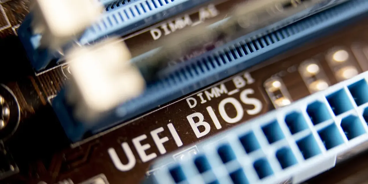 Zbliżenie na płytę główną z widocznym napisem "UEFI BIOS" i złączami RAM. W tle widać oznaczenie DIMM_A1, a poniżej DIMM_B1. Ten układ jest kluczowy dla bezpieczeństwa systemu, podobnie jak moduł **TPM 2.0**.