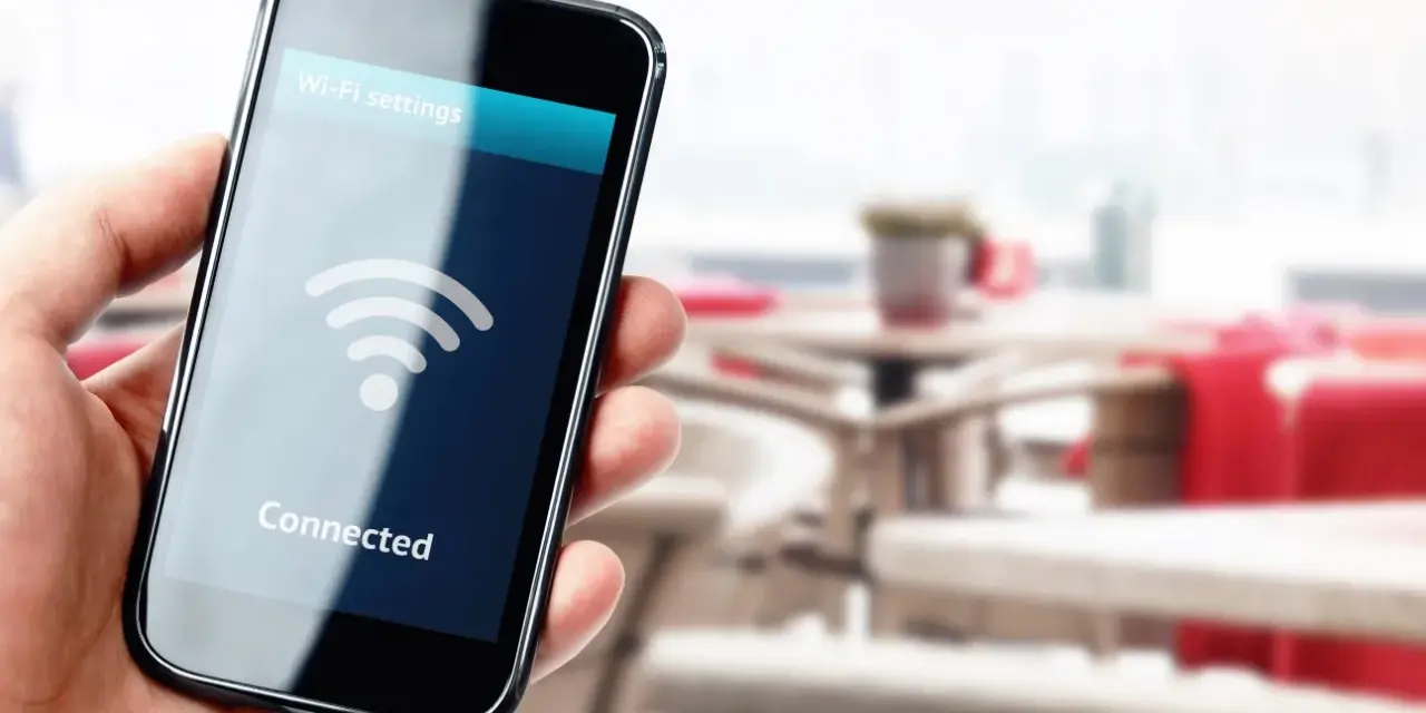 Dłoń trzyma smartfon z ikoną Wi-Fi i napisem "Connected".