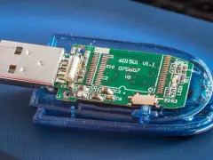 Rozłożony pendrive z widoczną zieloną płytką drukowaną i złączem USB. Widać elementy elektroniczne, oznaczenia jak "6015U1 V1.1" i "exfat" (choć nie widać go na obrazku, można założyć, że jest to format pliku).