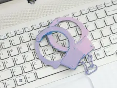 Różowe kajdanki na klawiaturze laptopa symbolizują problemy ze sklepem z aplikacjami.