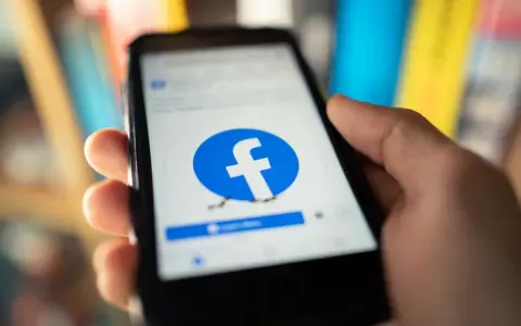 Dłoń trzyma smartfon z logo Facebooka. Chcesz wiedzieć, jak usunąć FB?