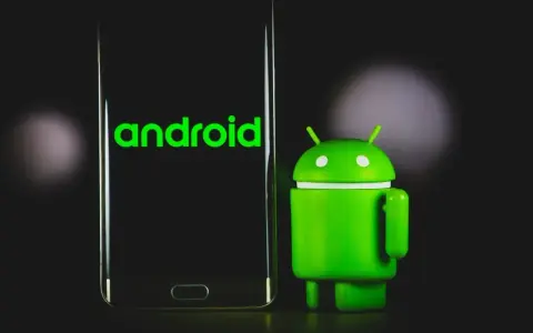 Zielony robot Android obok telefonu z logo Android 13.