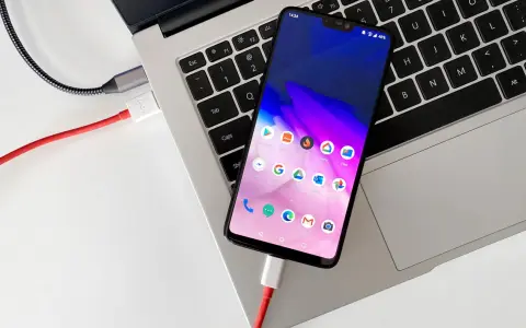 Smartfon podłączony kablem do laptopa, gotowy do przenoszenia zdjęć.