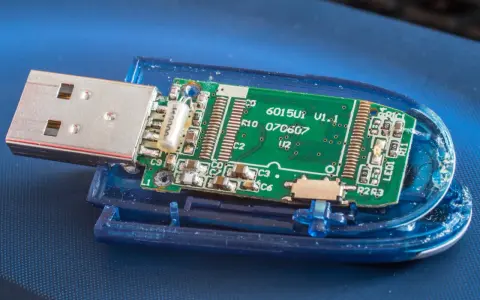 Rozłożony pendrive z widoczną zieloną płytką drukowaną i złączem USB. Widać elementy elektroniczne, oznaczenia jak "6015U1 V1.1" i "exfat" (choć nie widać go na obrazku, można założyć, że jest to format pliku).