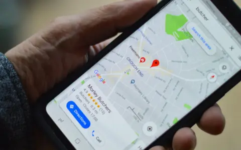 Dłoń trzyma smartfon z mapą Google, na której widoczny jest czerwony pinezka i nazwa "Morley Butchers".