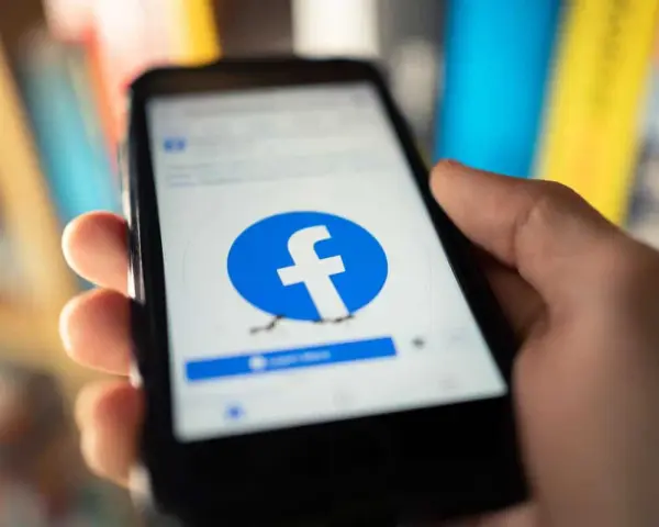 Dłoń trzyma smartfon z logo Facebooka. Chcesz wiedzieć, jak usunąć FB?