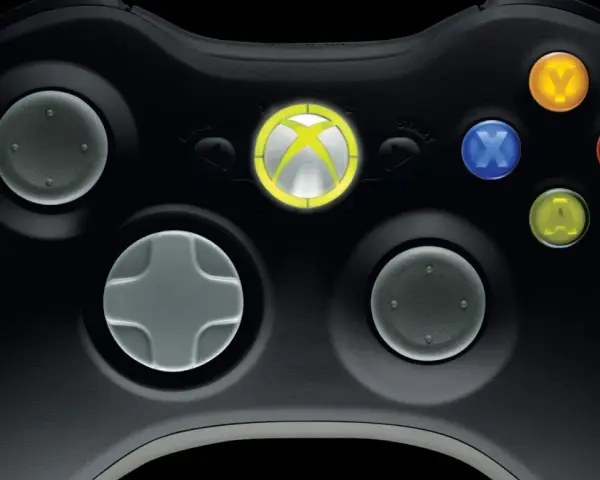 Zbliżenie na czarny kontroler Xbox 360 z podświetlonym logo Xbox i kolorowymi przyciskami.