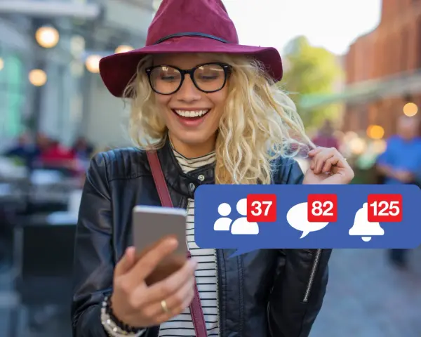 Szukasz informacji, jak usunąć konto na FB na telefonie? Uśmiechnięta dziewczyna z telefonem i powiadomieniami na ekranie.