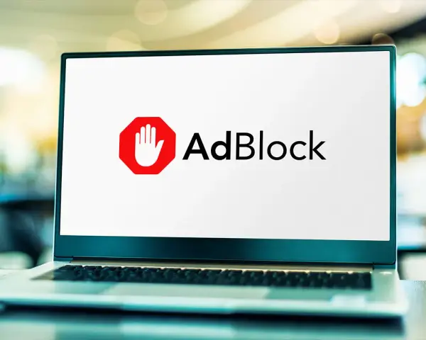 Laptop z logo AdBlock. Dowiedz się, jak wyłączyć adblocka, aby zobaczyć treści.