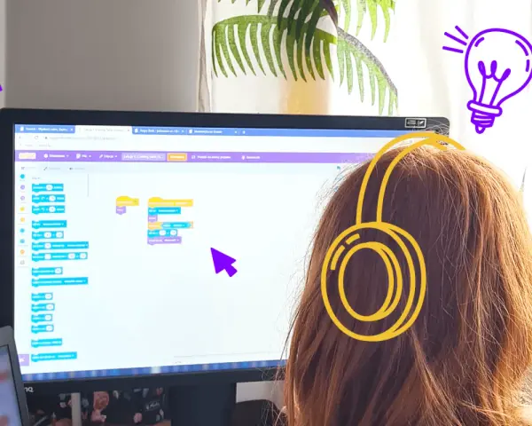 Dziewczynka w słuchawkach tworzy kod w Scratch po polsku, ucząc się programowania.
