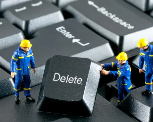Figurki robotników w niebieskich kombinezonach próbują usunąć klawisz "Delete" z klawiatury. Działają jak incogni, usuwając niechciane dane.