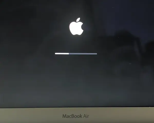 Ekran startowy MacBook Air z logo Apple i paskiem postępu, wskazującym ładowanie systemu macOS Monterey.