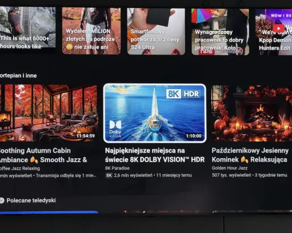 Ekran telewizora z interfejsem YouTube. Widać reklamy, w tym "Kpop Demon Hunters Edit", oraz filmy relaksacyjne, np. "Soothing Autumn Cabin". Użycie youtube adblock pozwala na oglądanie bez przerw.