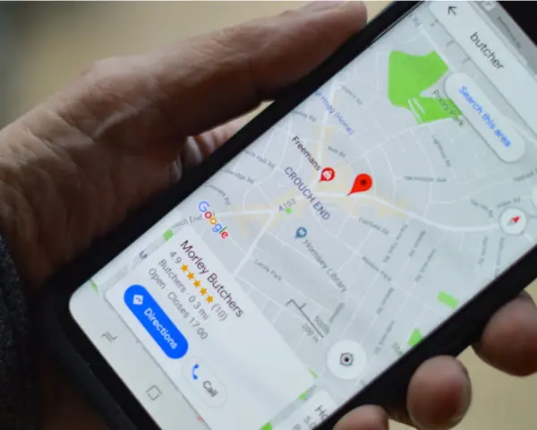 Dłoń trzyma smartfon z mapą Google, na której widoczny jest czerwony pinezka i nazwa "Morley Butchers".