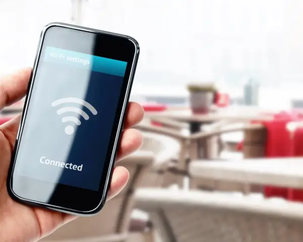Dłoń trzyma smartfon z ikoną Wi-Fi i napisem "Connected".