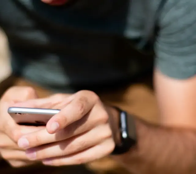 Mężczyzna z zegarkiem na ręku korzysta z telefonu, ucząc się, jak sparować zegarek z telefonem.
