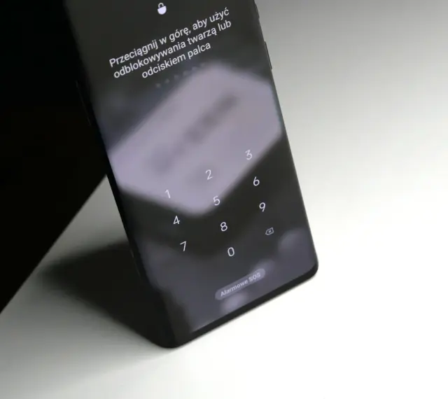 Ekran blokady Samsung z klawiaturą numeryczną i instrukcją "Przeciągnij w górę, aby użyć odblokowywania twarzą lub odciskiem palca". Pomoc, jak odblokować telefon Samsung, gdy zapomni się kodu.