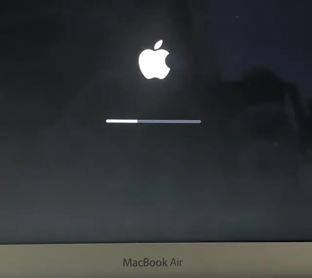 Ekran startowy MacBook Air z logo Apple i paskiem postępu, wskazującym ładowanie systemu macOS Monterey.