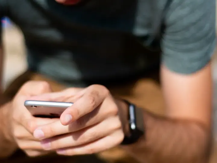 Mężczyzna z zegarkiem na ręku korzysta z telefonu, ucząc się, jak sparować zegarek z telefonem.