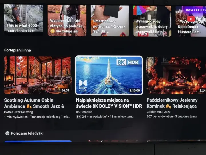 Ekran telewizora z interfejsem YouTube. Widać reklamy, w tym "Kpop Demon Hunters Edit", oraz filmy relaksacyjne, np. "Soothing Autumn Cabin". Użycie youtube adblock pozwala na oglądanie bez przerw.