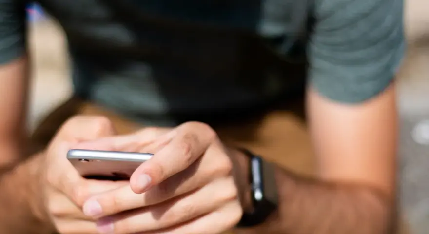 Mężczyzna z zegarkiem na ręku korzysta z telefonu, ucząc się, jak sparować zegarek z telefonem.