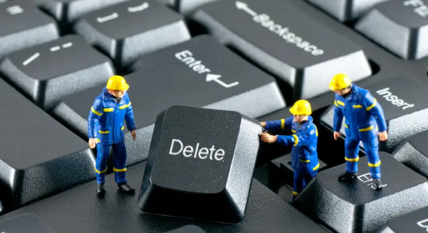 Figurki robotników w niebieskich kombinezonach próbują usunąć klawisz "Delete" z klawiatury. Działają jak incogni, usuwając niechciane dane.