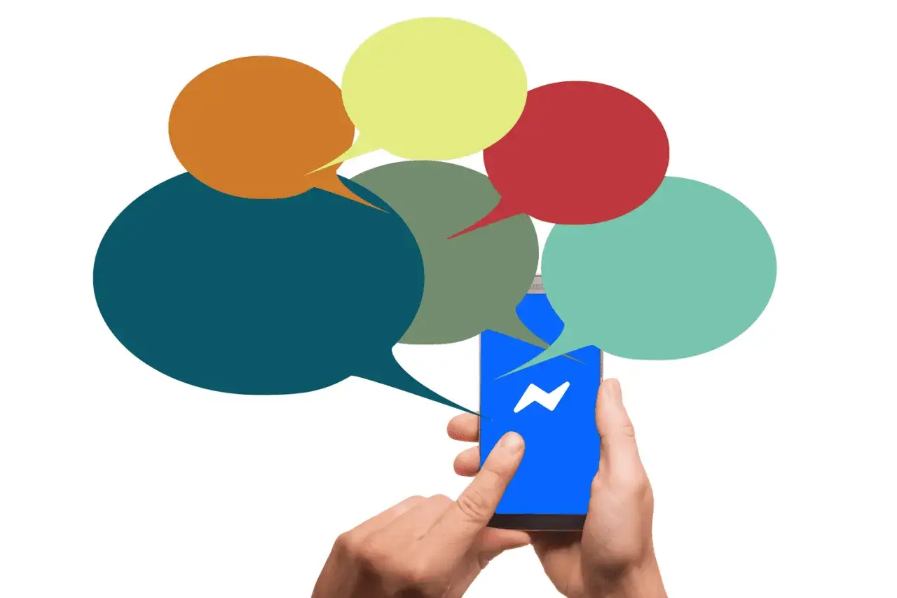 Dłoń trzyma smartfon z ikoną Messengera, otoczony kolorowymi dymkami. Szukasz sposobu, jak odzyskać usunięte wiadomości z Messengera?