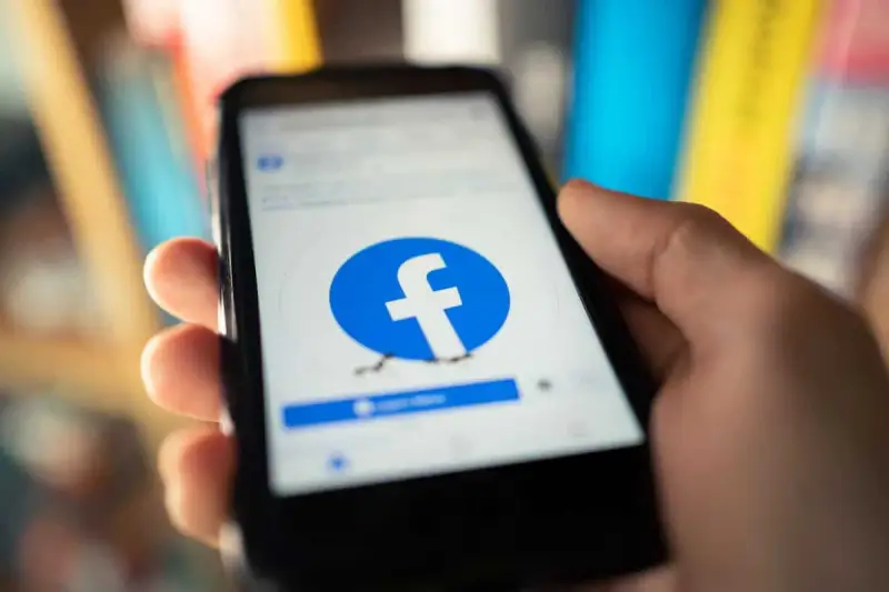 Dłoń trzyma smartfon z logo Facebooka. Chcesz wiedzieć, jak usunąć FB?