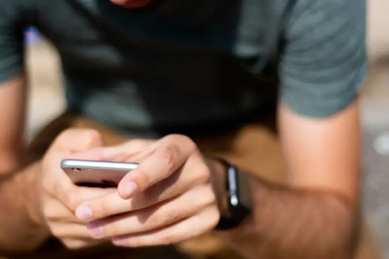 Mężczyzna z zegarkiem na ręku korzysta z telefonu, ucząc się, jak sparować zegarek z telefonem.